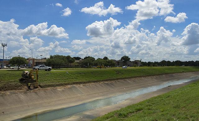 An excavator digs at the edge of Brays Bayou in Houston